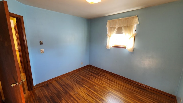 spare room featuring wood finished floors and baseboards