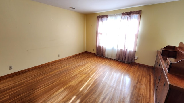 unfurnished room with baseboards and wood finished floors