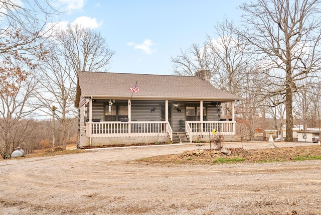 view of front of property featuring a shingled roof, dirt driveway, a porch, and a ceiling fan