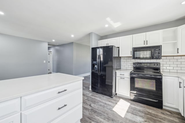 kitchen featuring tasteful backsplash, light countertops, light wood-style flooring, white cabinets, and black appliances