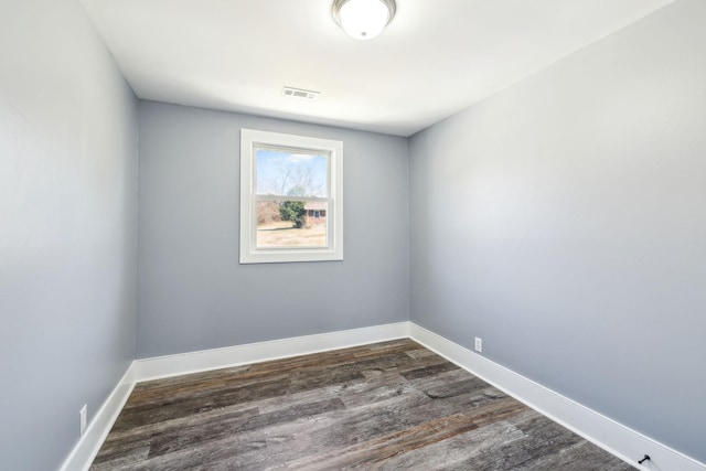 unfurnished room with visible vents, dark wood finished floors, and baseboards