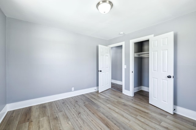 unfurnished bedroom with light wood-type flooring, a closet, and baseboards