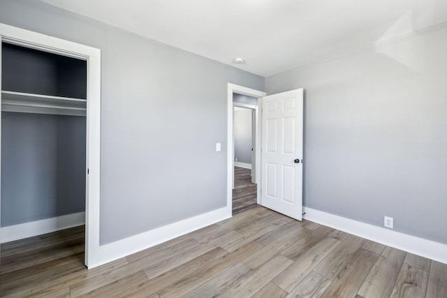 unfurnished bedroom with a closet, baseboards, and wood finished floors