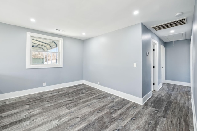 unfurnished room featuring baseboards, attic access, visible vents, and wood finished floors