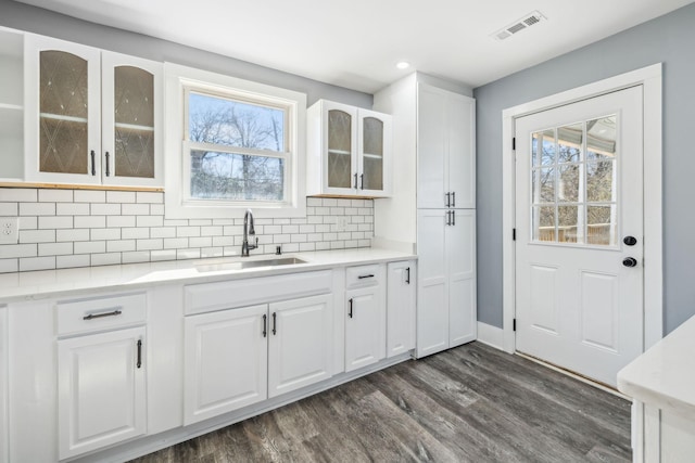 kitchen featuring visible vents, decorative backsplash, dark wood finished floors, white cabinetry, and a sink