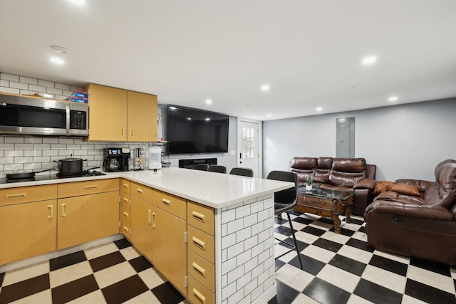 kitchen featuring a peninsula, open floor plan, light countertops, light floors, and stainless steel microwave