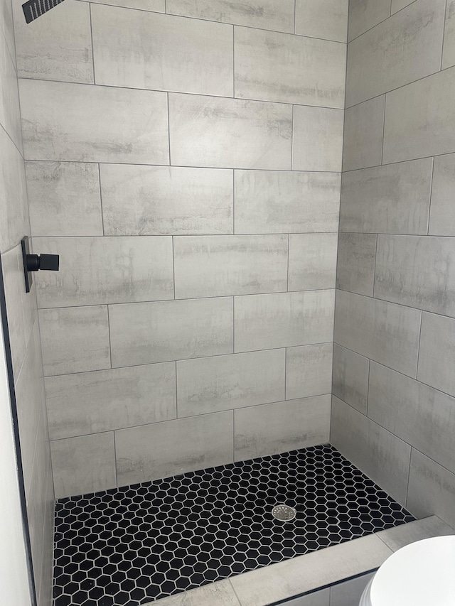 bathroom with a tile shower and toilet