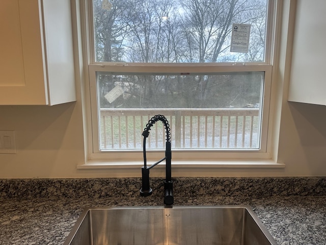 room details with dark stone counters, white cabinetry, and a sink