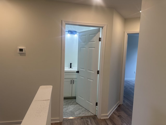 corridor featuring dark wood-type flooring and baseboards