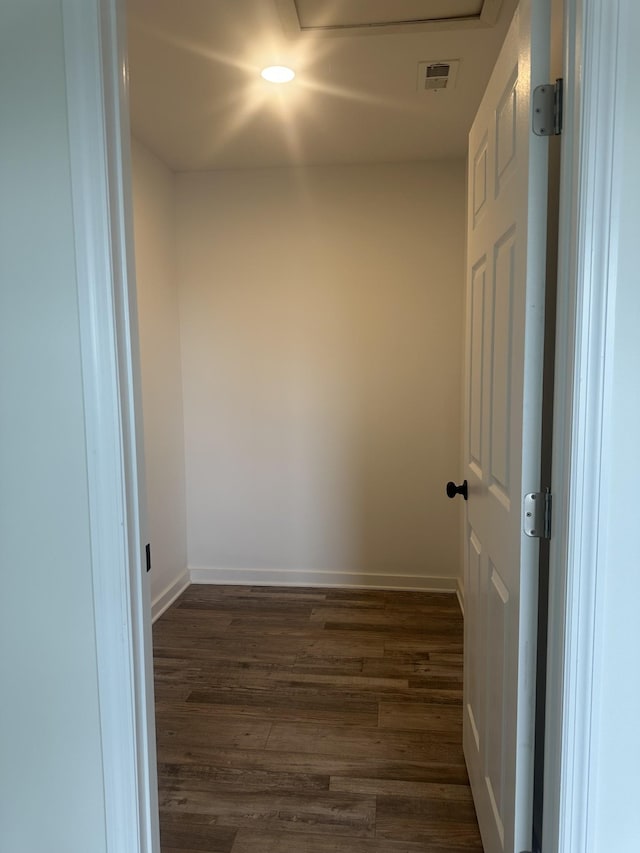 empty room featuring attic access, visible vents, baseboards, and dark wood-type flooring