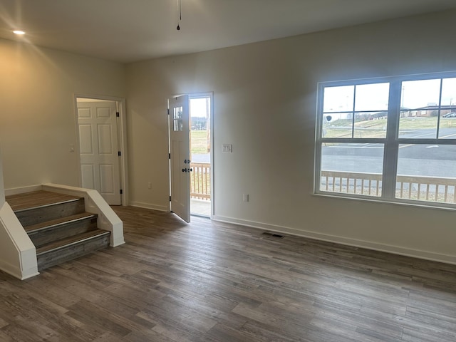 spare room featuring stairway, dark wood finished floors, visible vents, and baseboards