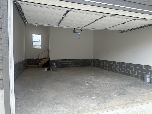 garage with concrete block wall and a garage door opener