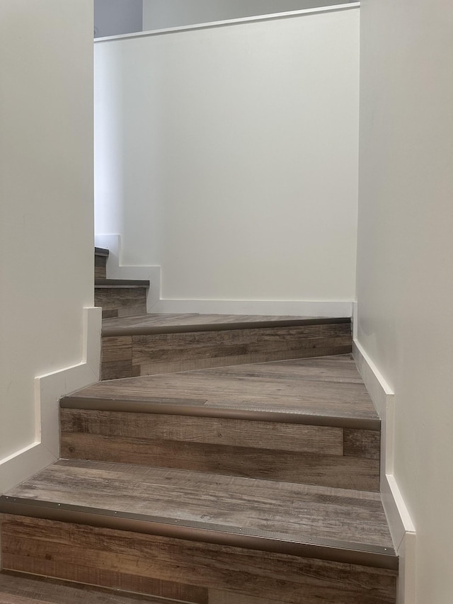 stairway with wood finished floors and baseboards