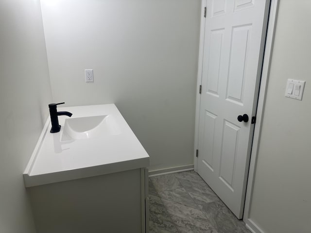 bathroom with marble finish floor, vanity, and baseboards