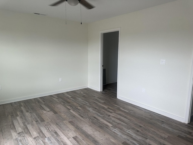 empty room with a ceiling fan, dark wood-style flooring, visible vents, and baseboards