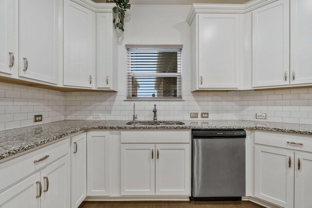 kitchen featuring light stone counters, tasteful backsplash, white cabinetry, a sink, and dishwasher