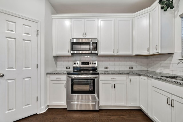 kitchen featuring appliances with stainless steel finishes, dark wood-type flooring, a sink, and white cabinets