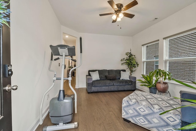 exercise area featuring baseboards, wood finished floors, visible vents, and a ceiling fan