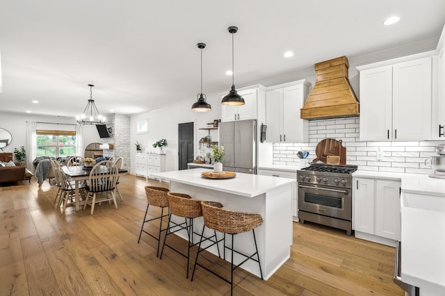 kitchen featuring a kitchen island, custom range hood, appliances with stainless steel finishes, a breakfast bar, and light wood-style floors