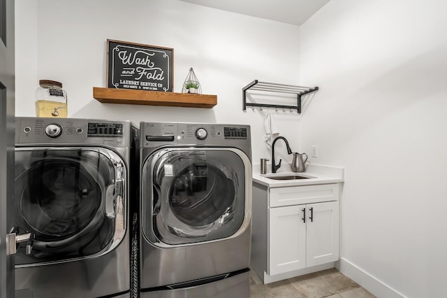 laundry area featuring cabinet space, baseboards, separate washer and dryer, a sink, and light tile patterned flooring