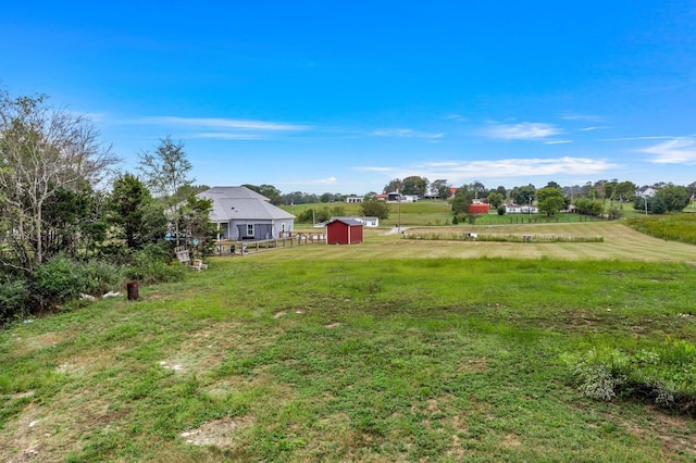 view of yard with a rural view, an outdoor structure, and a storage shed