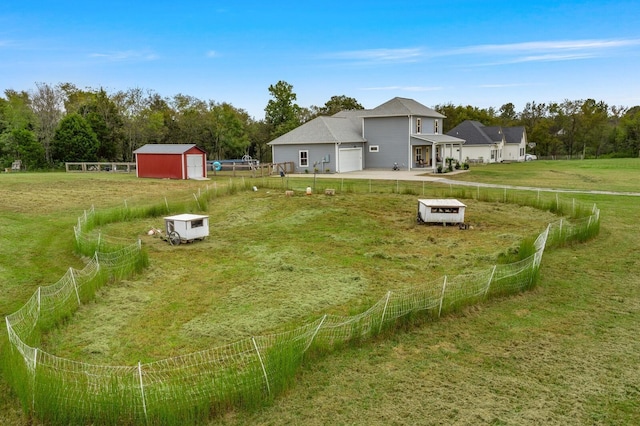 view of yard with driveway, a garage, fence, and an outbuilding