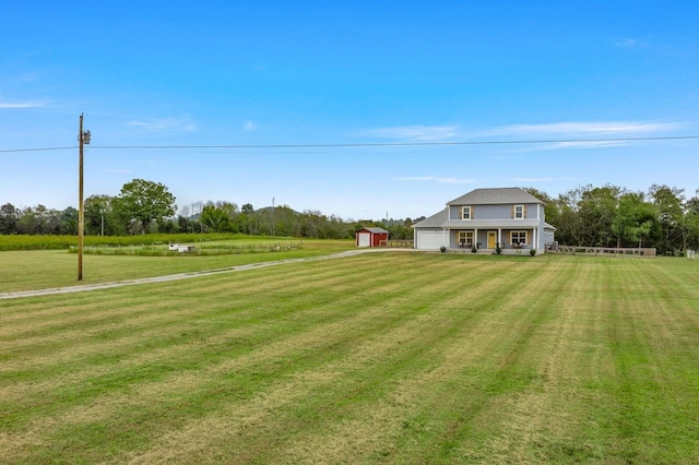 view of yard with driveway, a garage, and an outbuilding