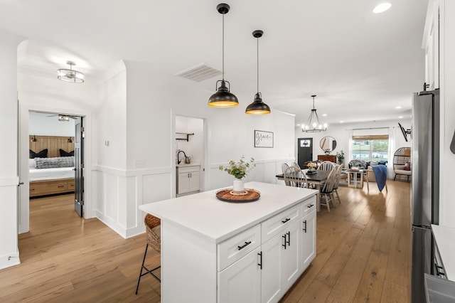 kitchen featuring visible vents, light wood-type flooring, freestanding refrigerator, and white cabinets