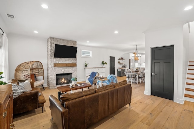 living area featuring a stone fireplace, light wood finished floors, visible vents, and recessed lighting