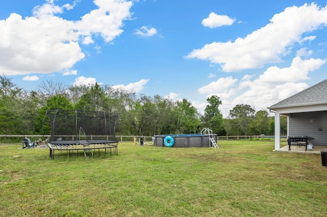 view of yard featuring a trampoline and fence