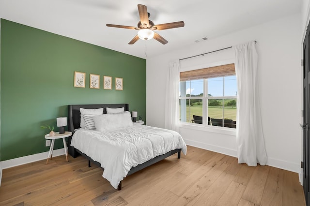 bedroom featuring light wood finished floors, baseboards, visible vents, and a ceiling fan