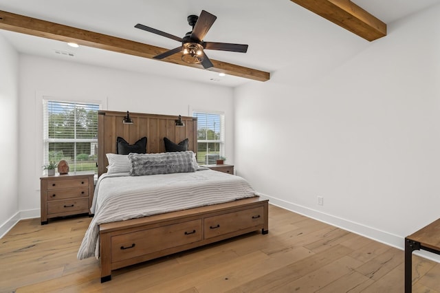 bedroom with light wood-style flooring, baseboards, and beamed ceiling