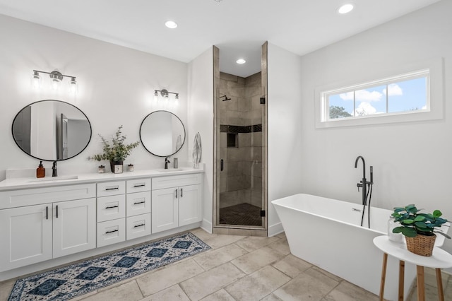 bathroom featuring double vanity, a freestanding tub, a stall shower, and a sink