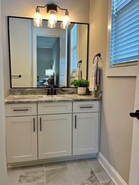 ensuite bathroom with marble finish floor, ensuite bath, vanity, and baseboards