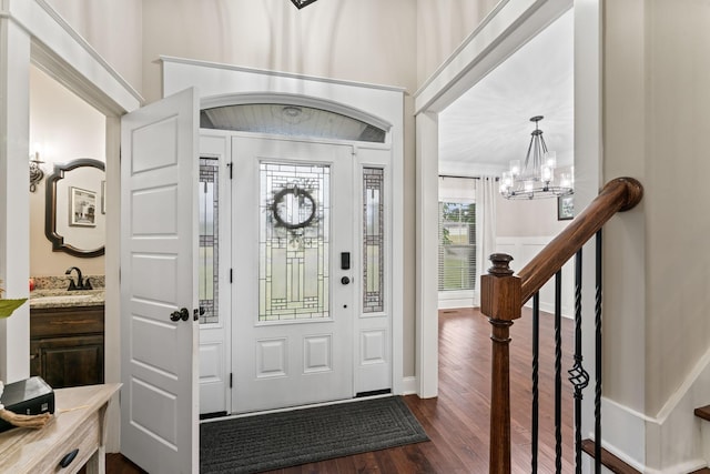 foyer featuring dark wood-style floors, a chandelier, crown molding, and stairs