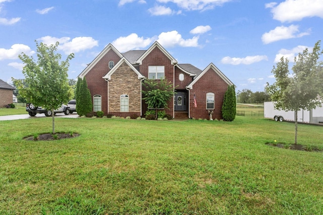 view of front of property featuring a front yard, brick siding, and fence