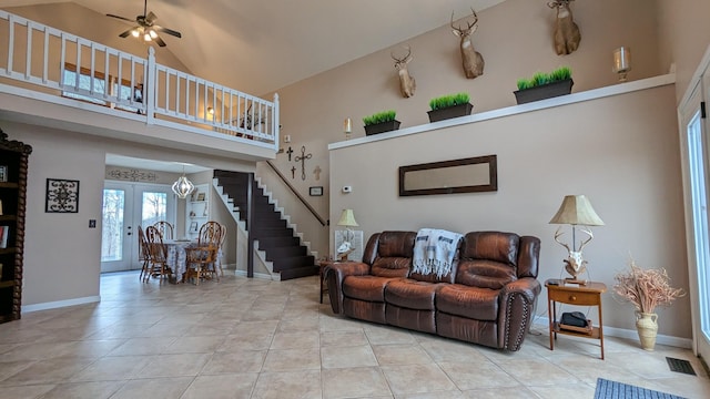 living area featuring light tile patterned floors, visible vents, stairway, high vaulted ceiling, and baseboards