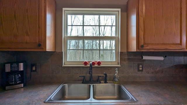 kitchen featuring backsplash, a sink, and brown cabinetry