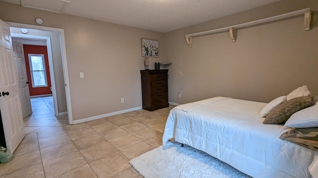 bedroom featuring light tile patterned floors, attic access, and baseboards