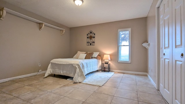 bedroom with light tile patterned floors and baseboards