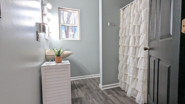 full bathroom featuring curtained shower, baseboards, and wood finished floors