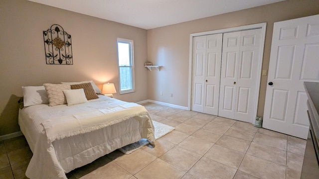 bedroom with light tile patterned floors, baseboards, and a closet