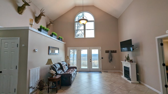 entrance foyer featuring light tile patterned floors, high vaulted ceiling, a fireplace, visible vents, and french doors