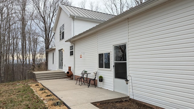 back of property with metal roof and a patio