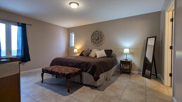 bedroom featuring baseboards, a textured ceiling, and light tile patterned flooring