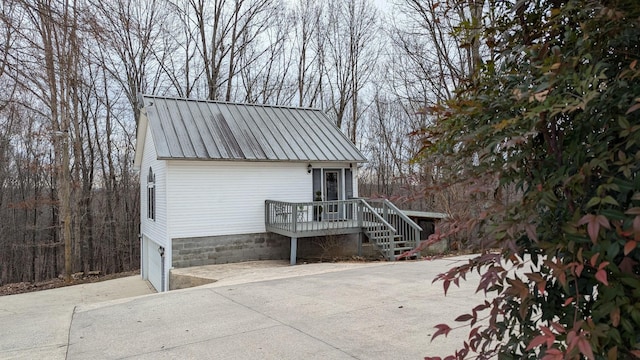 view of front facade with a garage, concrete driveway, metal roof, and stairs