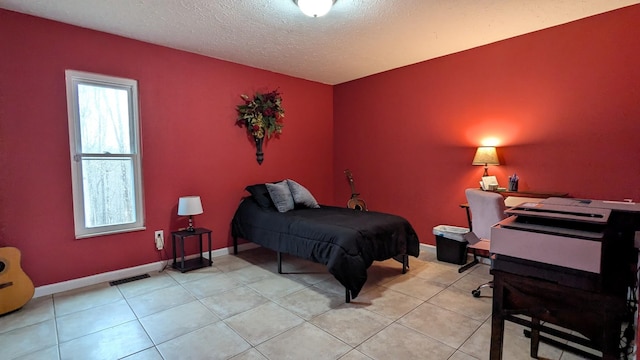 bedroom with a textured ceiling, light tile patterned flooring, visible vents, and baseboards