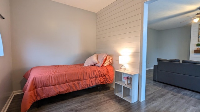 bedroom with wood walls, a ceiling fan, and wood finished floors