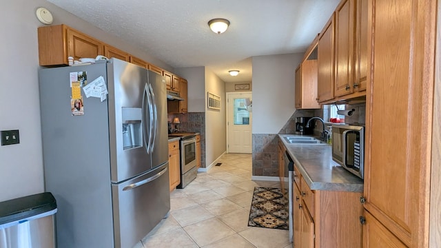 kitchen featuring stainless steel appliances, brown cabinetry, a sink, and decorative backsplash