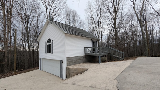 view of side of property featuring stairs, metal roof, a standing seam roof, and an attached garage